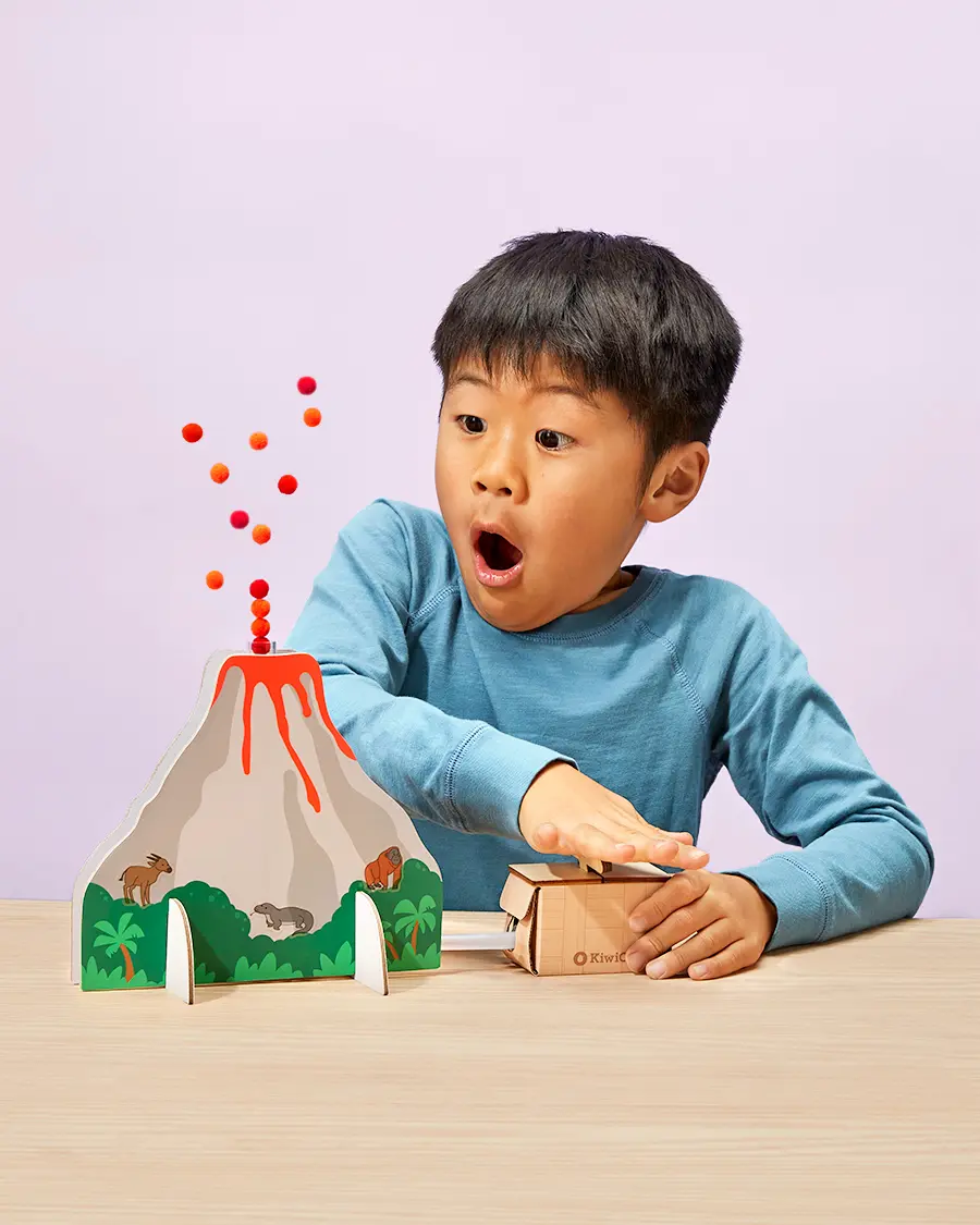 kid making volcano erupt with pom poms